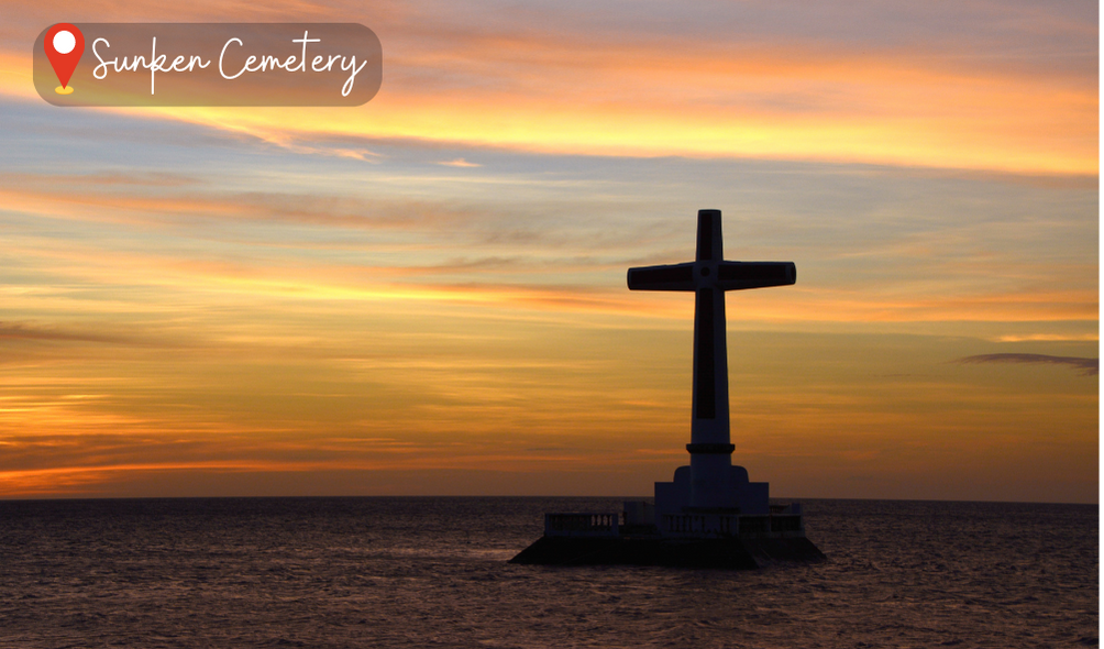 The image shows the Sunken Cemetery in Camiguin Island, Philippines. The cemetery is located off the coast of the island, with only a large cross visible above the water's surface. The cross marks the site of the old cemetery, which sank due to a volcanic eruption in the 1870s. The surrounding water is crystal clear and teeming with marine life, including colorful fish and coral reefs. The sunlight casts a golden glow over the scene, creating a serene and tranquil atmosphere. It's a hauntingly beautiful view that tells the story of the island's history and showcases the unique natural wonders of the Philippines. #SunkenCemetery #CamiguinIsland #Philippines #UnderwaterHeritage #VolcanicEruption #MarineLife #CoralReefs #NaturalWonders #History #TravelPH